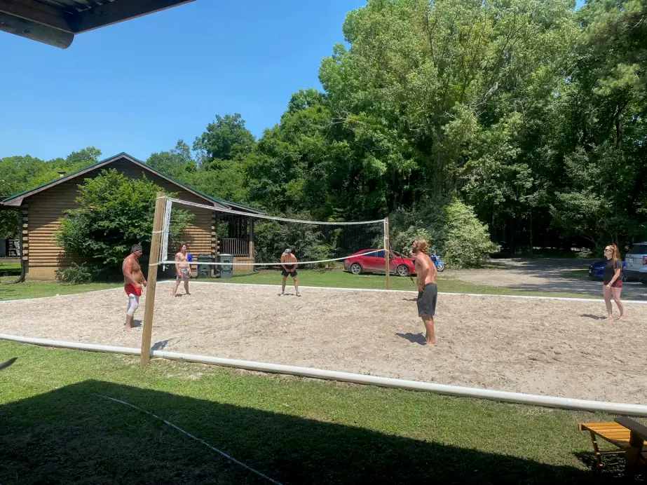Residents playing sand volleyball beside the Still Worthy cabin