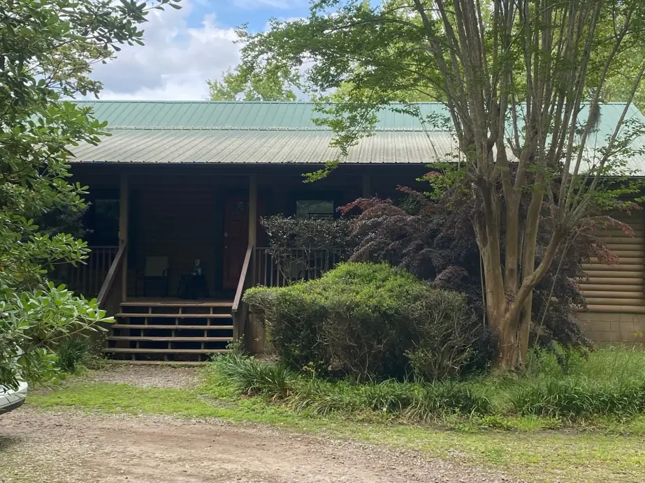 The front steps of a Still Worthy log cabin under a crepe myrtle