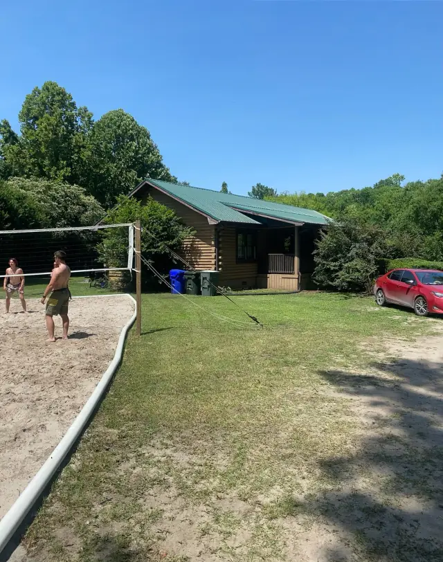 Sand volleyball court in front of the green-roofed log cabin